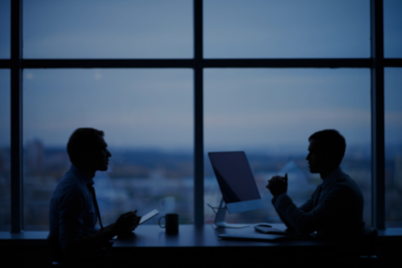 Two people talking at a desk